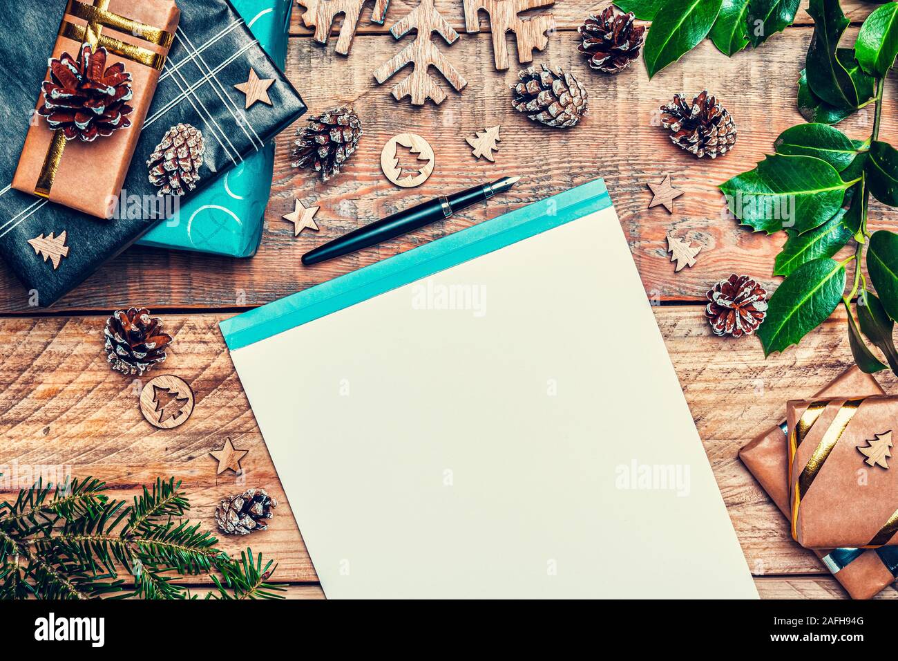 Lettera di Natale di Santa Claus concetto. Piano di composizione dei laici con carta da scrivere, penna, il cono di pini, avvolto di regali e decorazioni di Natale. Foto Stock