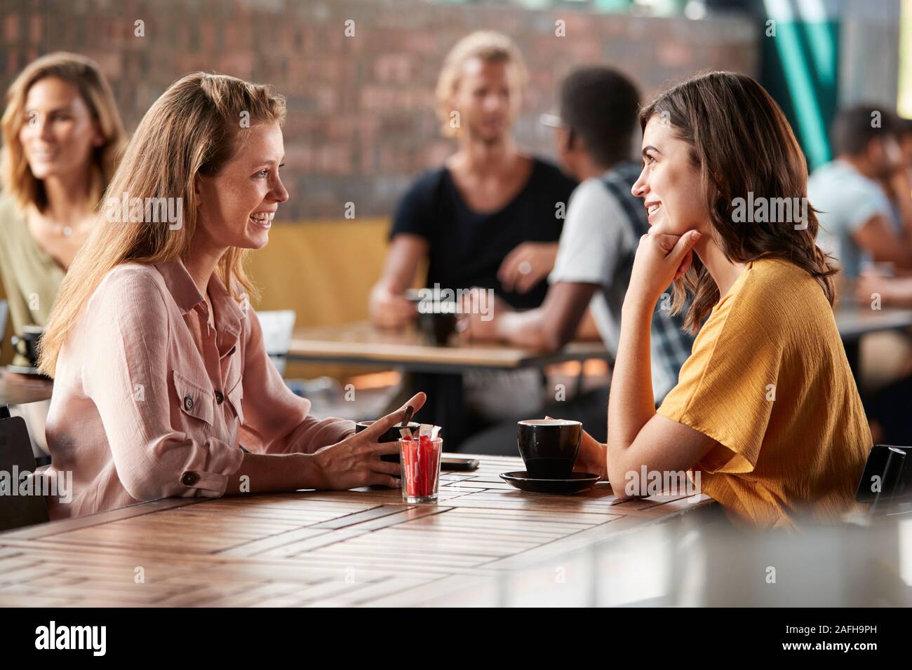 Due amiche seduta a tavola in un Coffee Shop e parlare Foto Stock