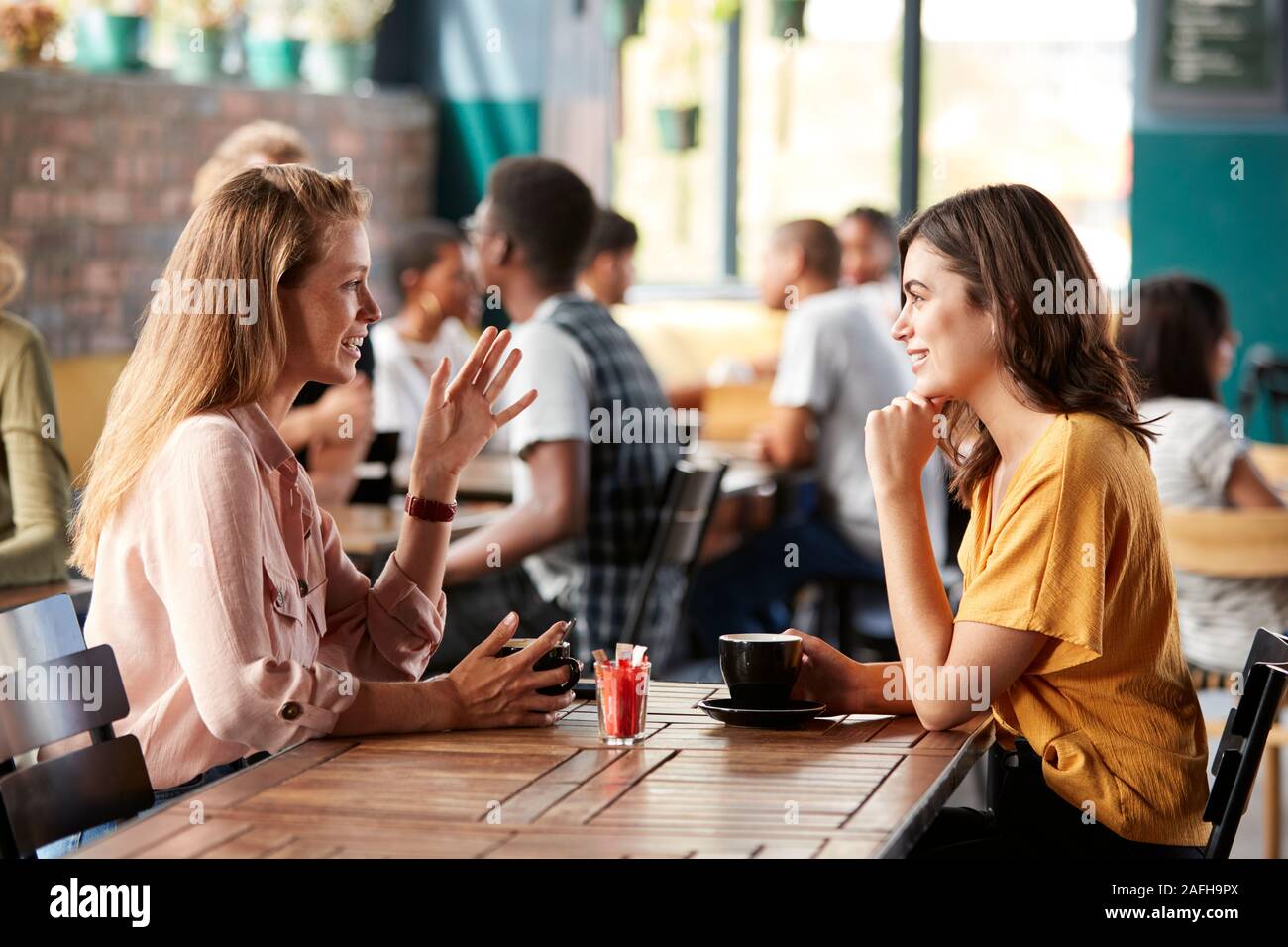 Due amiche seduta a tavola in un Coffee Shop e parlare Foto Stock