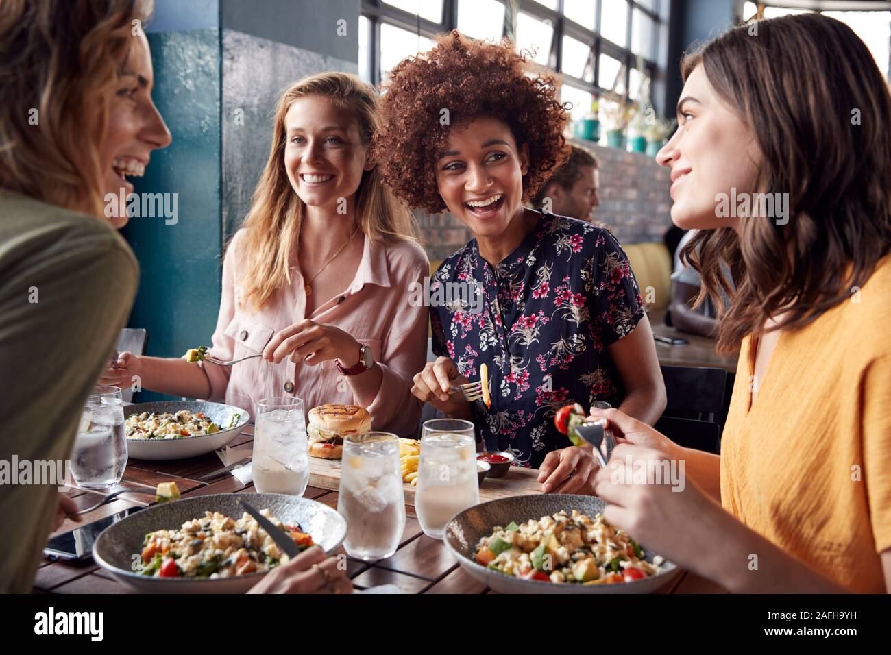 Quattro giovani amici di sesso femminile incontro per un drink e il cibo facendo un toast in Ristorante Foto Stock