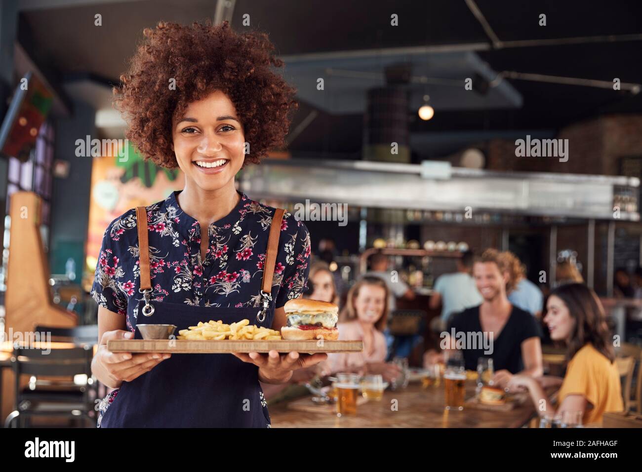 Ritratto di cameriera che serve cibo ai clienti nella trafficata Bar Ristorante Foto Stock