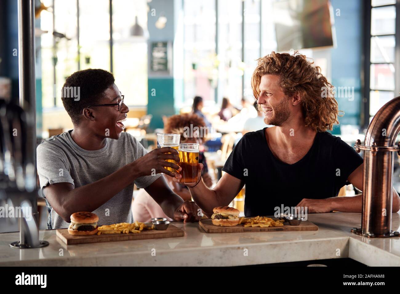 Due amici maschi Mangiare e bere birra nel bar sport Foto Stock
