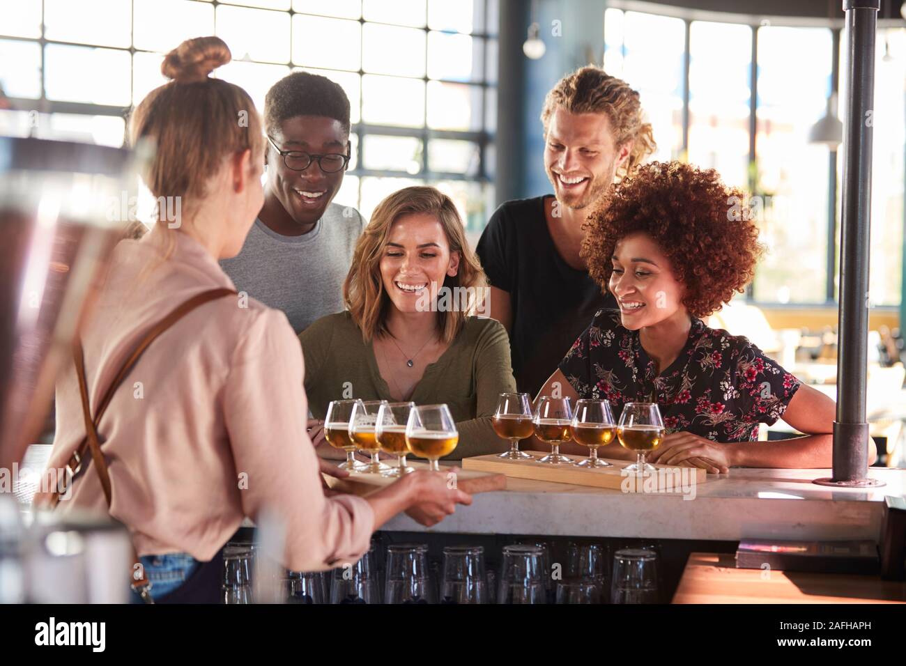 La cameriera che serve un gruppo di amici Degustazione di birra nel bar Foto Stock