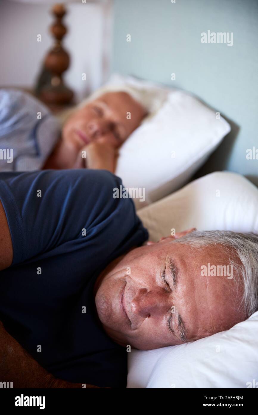 Senior bianco giovane addormentato nel loro letto, close up, verticale Foto Stock