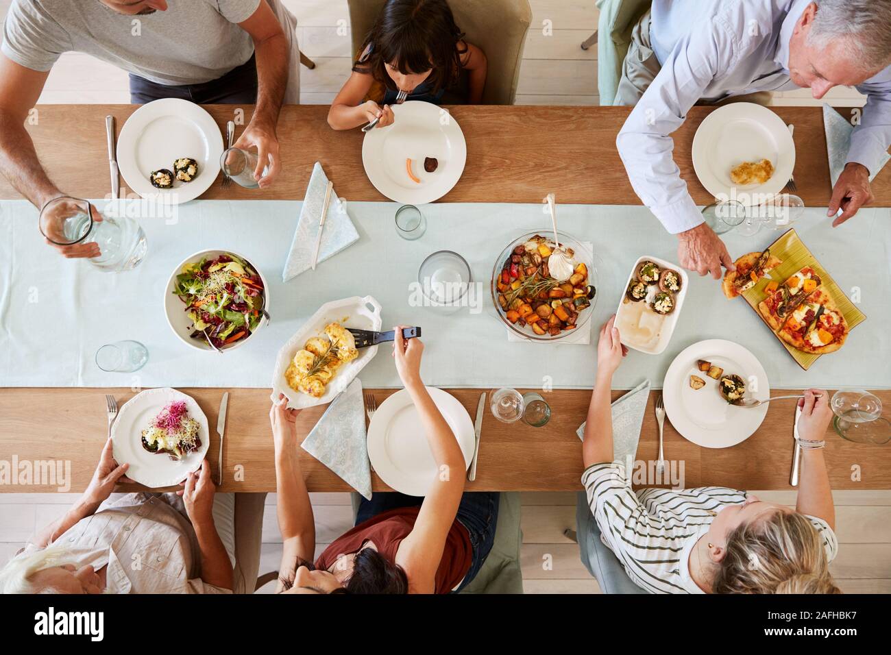 Tre generazioni della famiglia Bianchi seduti ad un tavolo per la cena insieme di servire un pasto, vista aerea Foto Stock