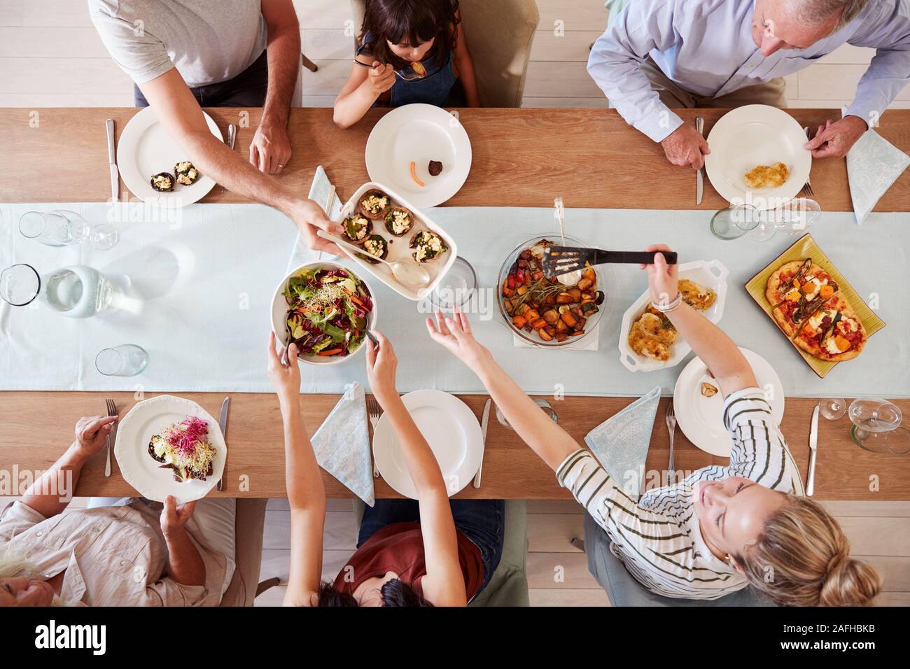Tre generazioni della famiglia Bianchi seduti ad un tavolo per la cena insieme di servire un pasto, vista aerea Foto Stock