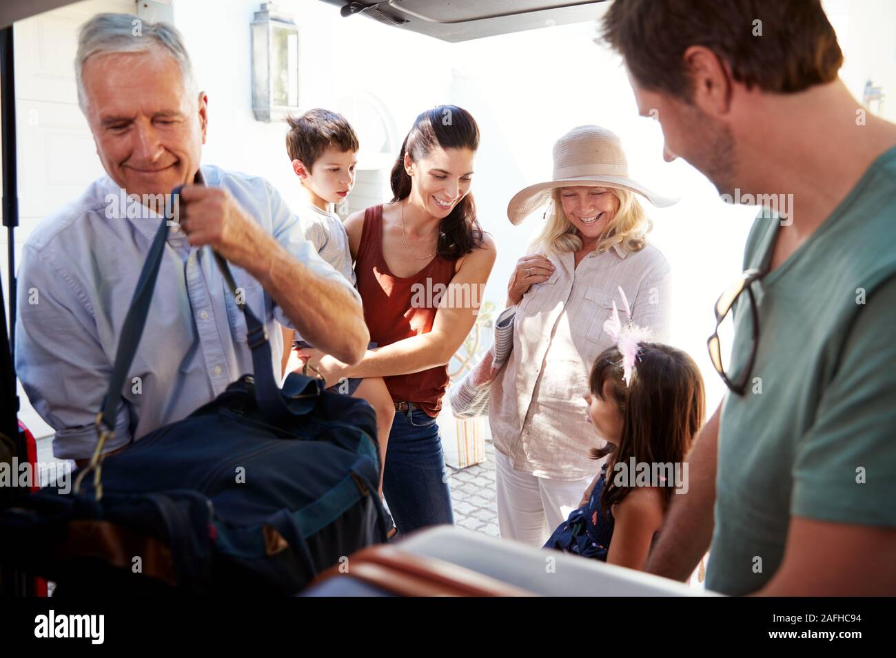 Nonno e papà di imballaggio avvio auto con i bagagli per le vacanze, mentre la famiglia attendere vicino, close up Foto Stock