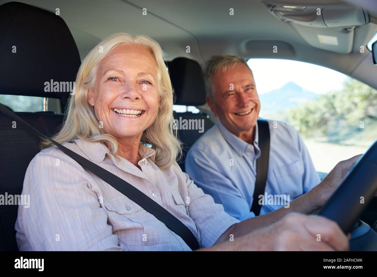 Senior donna bianca e suo marito la guida nella loro auto sorridente alla telecamera, vicino, vista laterale Foto Stock