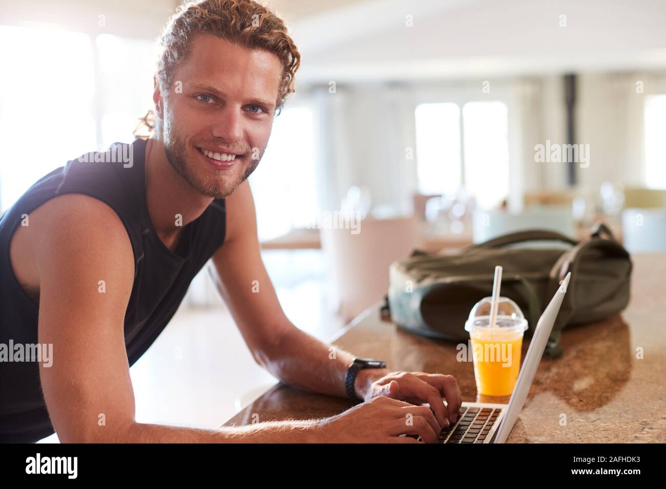 Millenaria uomo bianco controllo app fitness sul portatile a casa dopo un allenamento, sorridente alla fotocamera Foto Stock