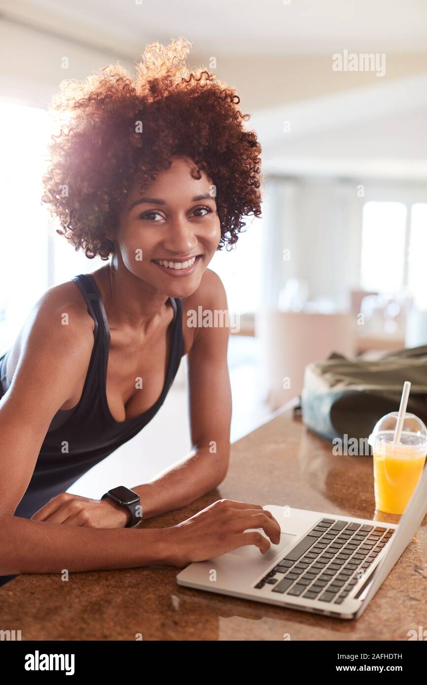 La millenaria americano africano donna verifica i dati di fitness sul computer che sorride alla telecamera, verticale Foto Stock