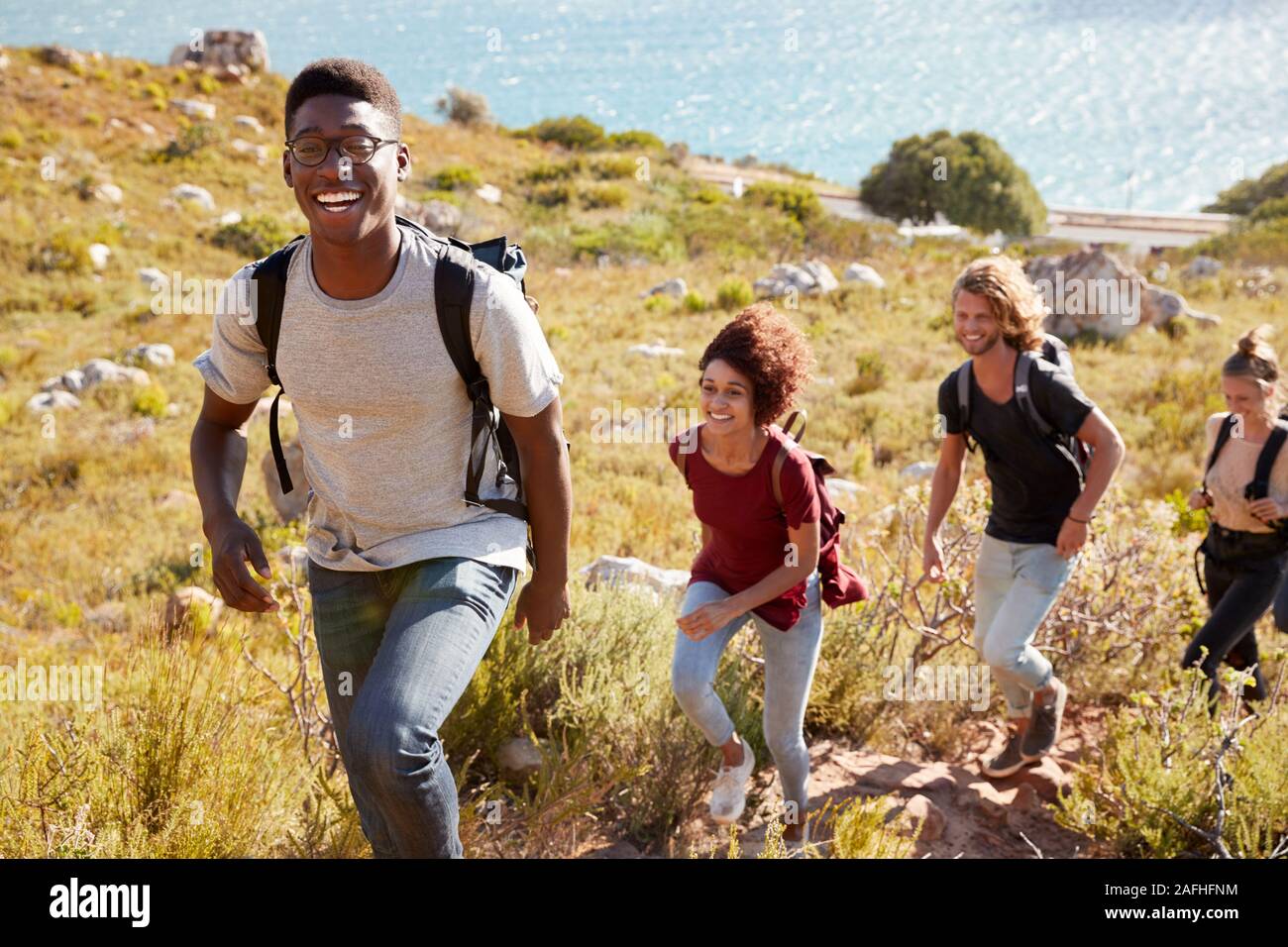La millenaria African American uomo porta una escursione dalla costa con gli amici, sorridente alla fotocamera Foto Stock