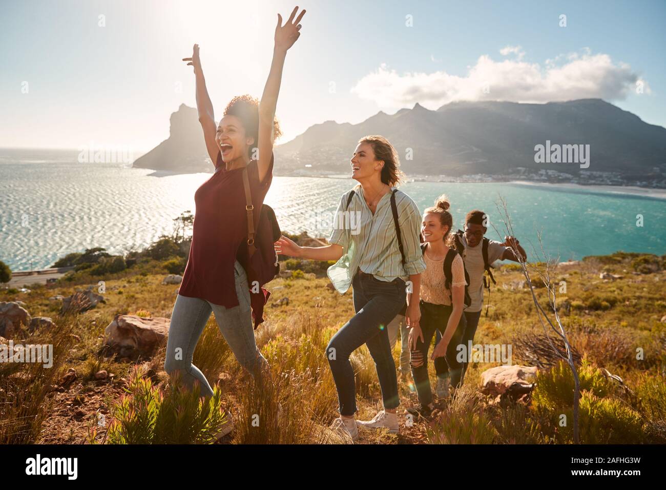 Giovani amici adulti escursionismo file singolo in salita per celebrare il raggiungimento di un vertice a piena lunghezza e vista laterale Foto Stock