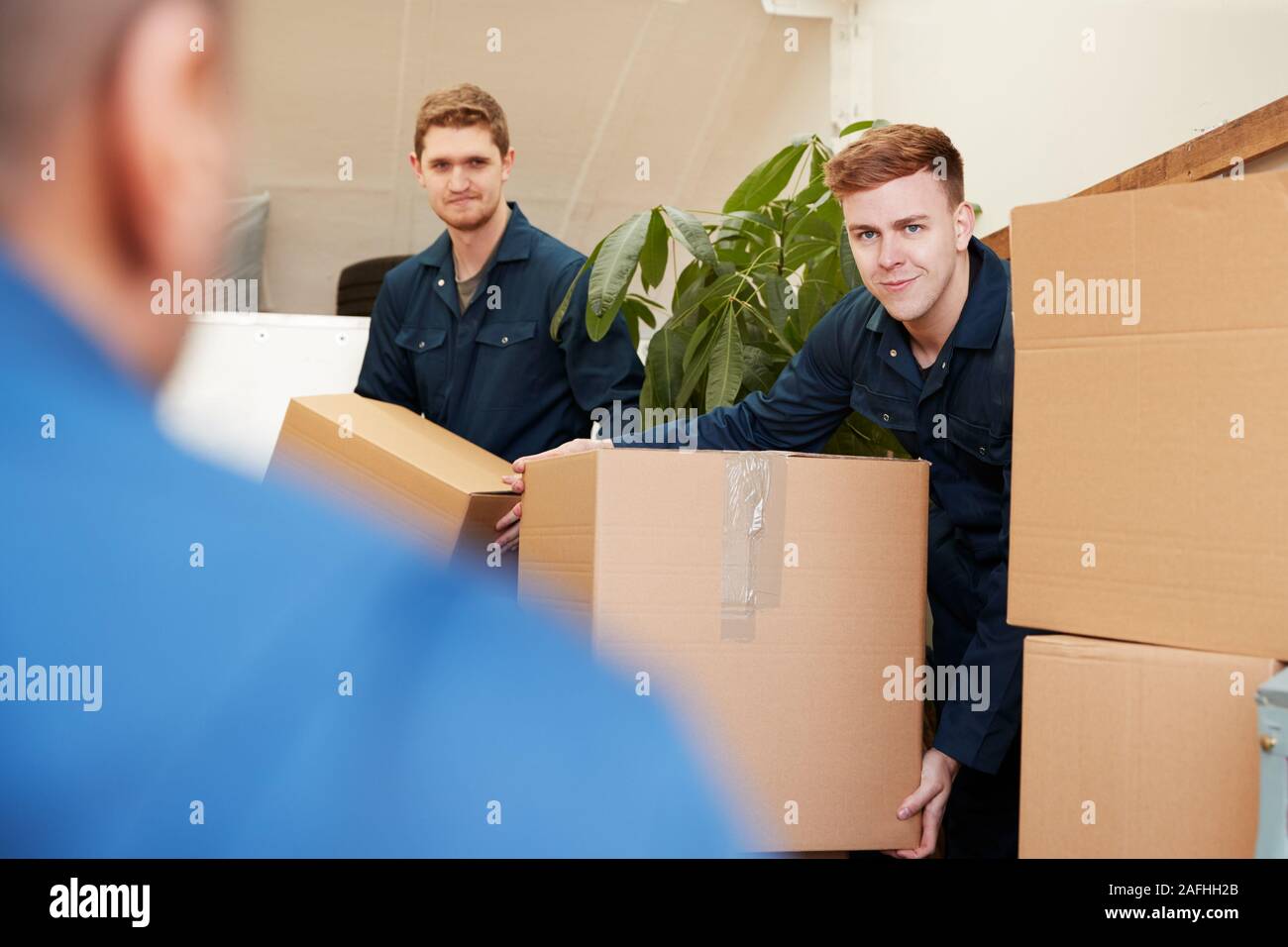 Distacco dei lavoratori della compagnia di mobili di scarico e scatole dal carrello nella nuova casa il giorno del trasloco Foto Stock