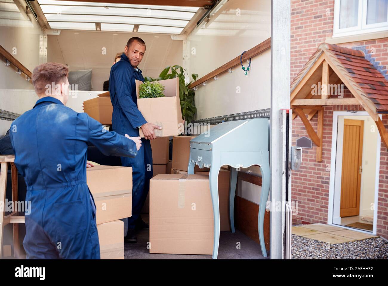 Distacco dei lavoratori della compagnia di mobili di scarico e scatole dal carrello nella nuova casa il giorno del trasloco Foto Stock