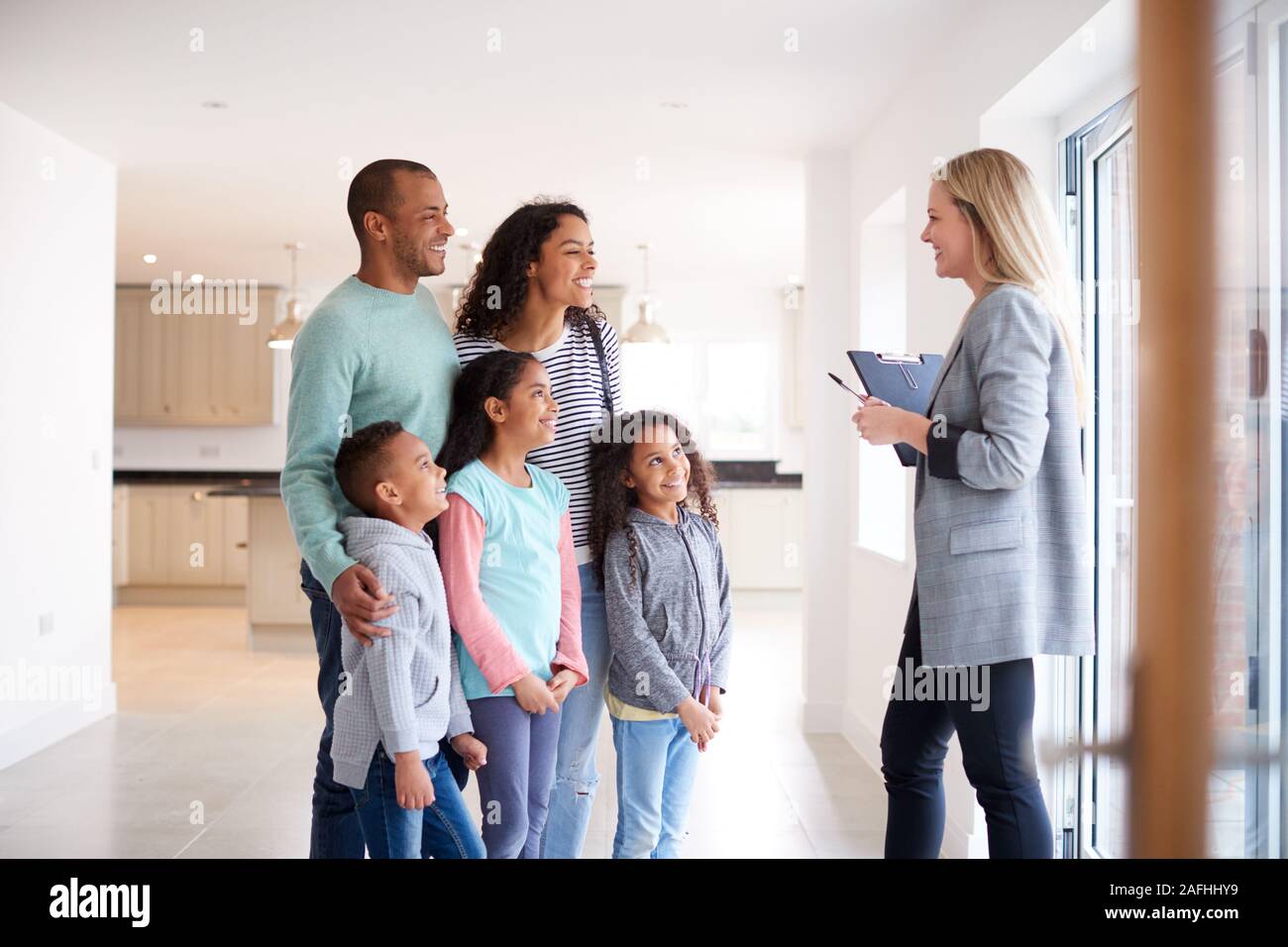 Agente immobiliare femmina Mostra famiglia interessati ad acquistare intorno a casa Foto Stock