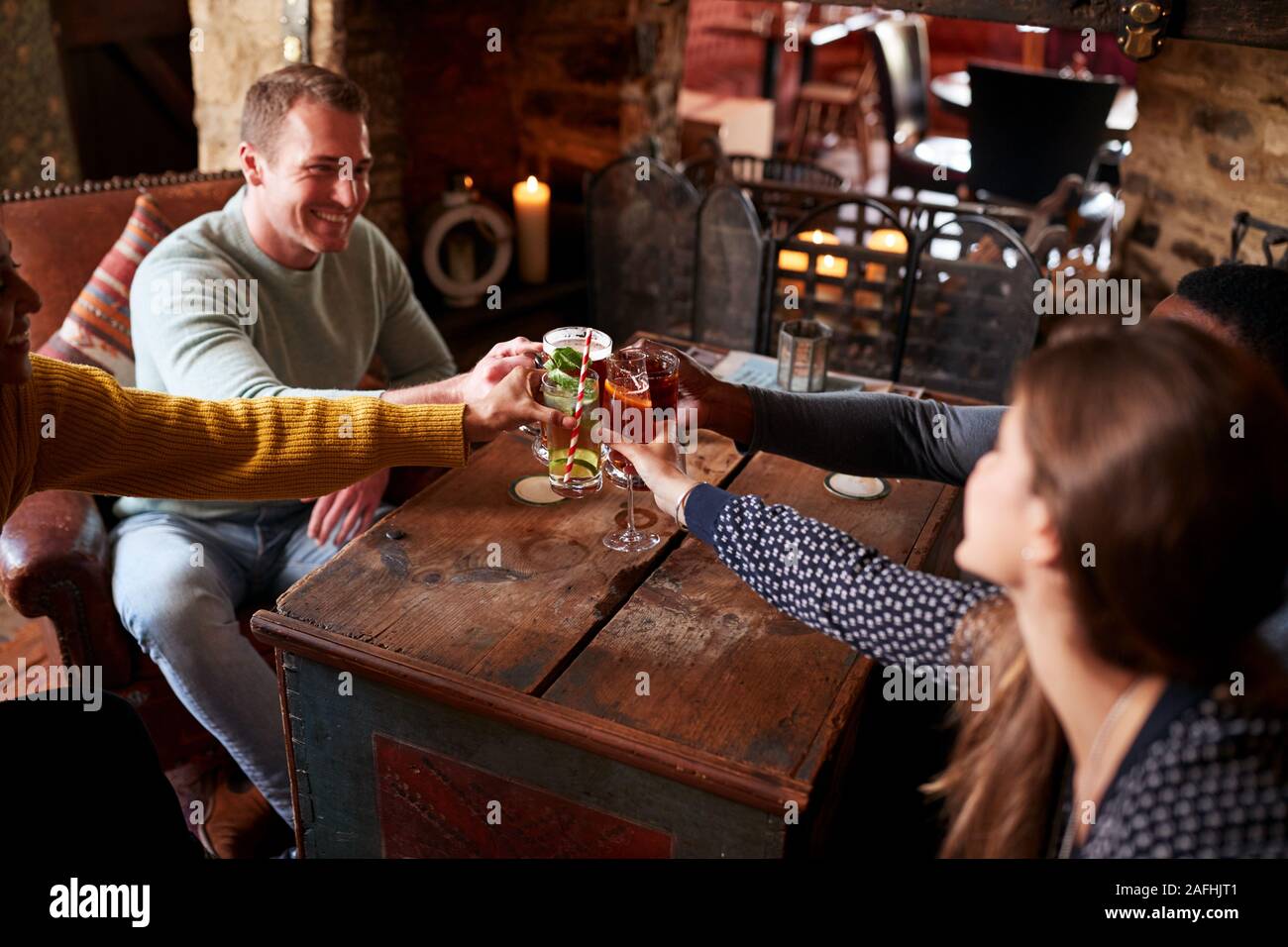 Gruppo di amici fare Toast come si incontrano per pranzo bevande nel tradizionale Pub Inglese Foto Stock