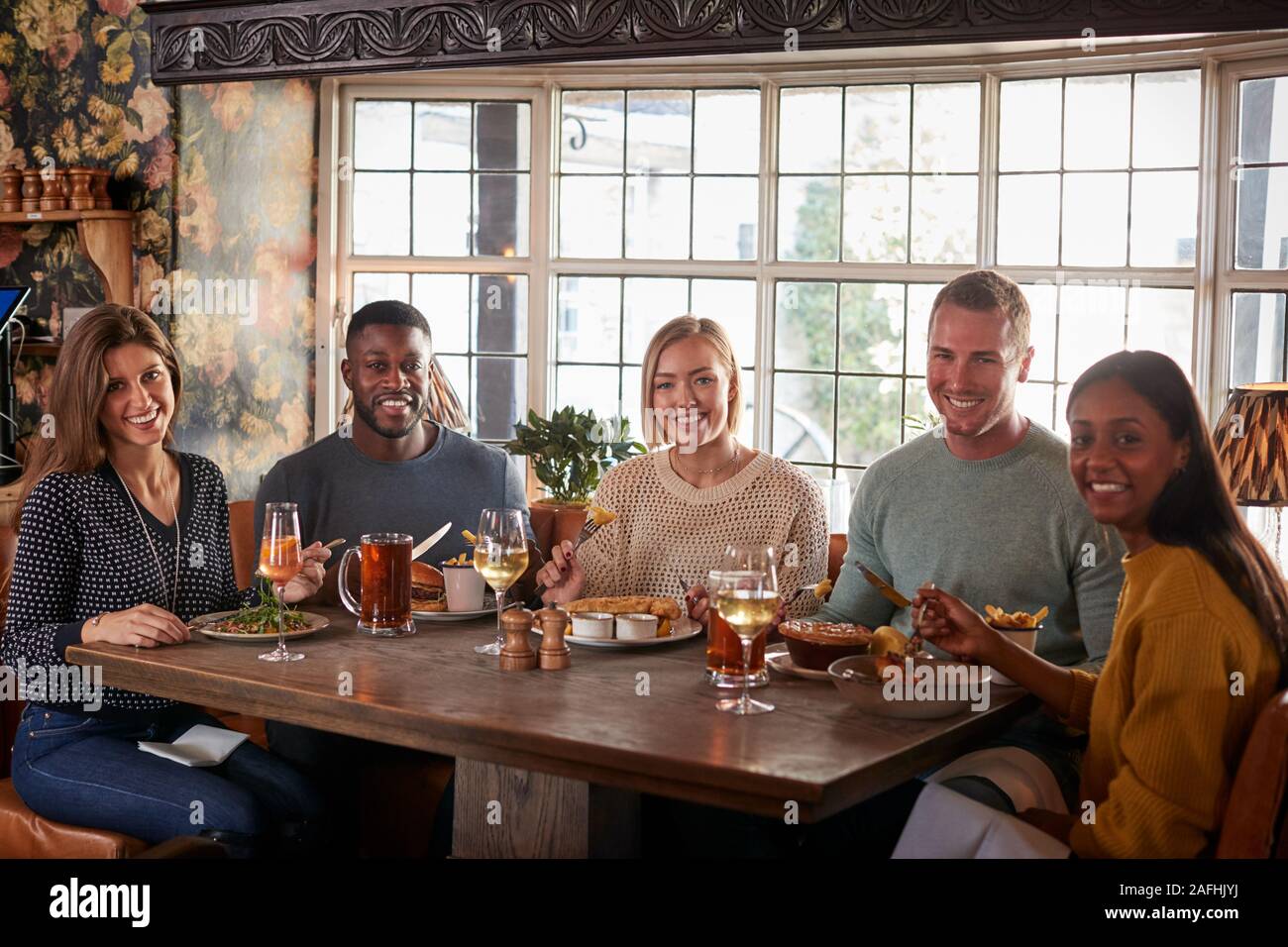 Ritratto di amici riuniti per il pasto in un tradizionale pub inglese Foto Stock