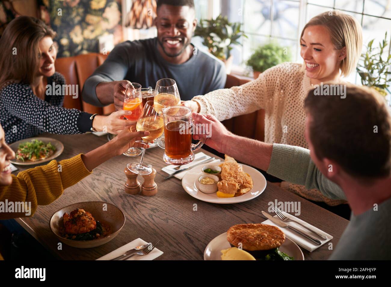 Riunione amici per il pasto in un tradizionale Pub Inglese rendendo brindare insieme Foto Stock