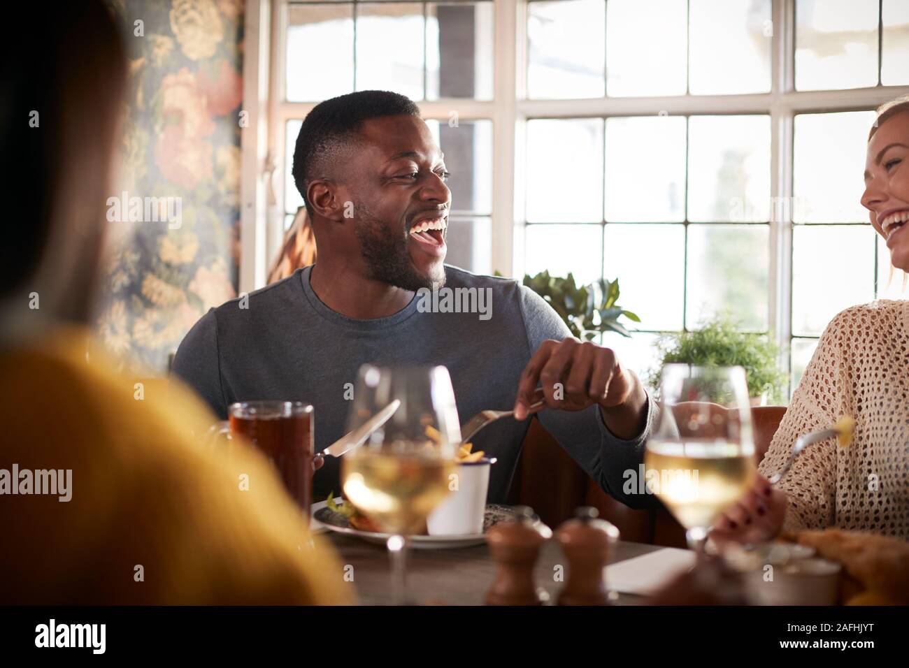 Gruppo di amici riuniti per il pasto in un tradizionale pub inglese Foto Stock