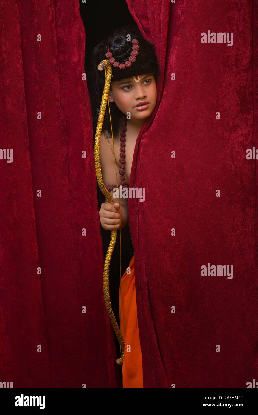 Bambino vestito come signore di ram che spuntavano di tende Foto Stock