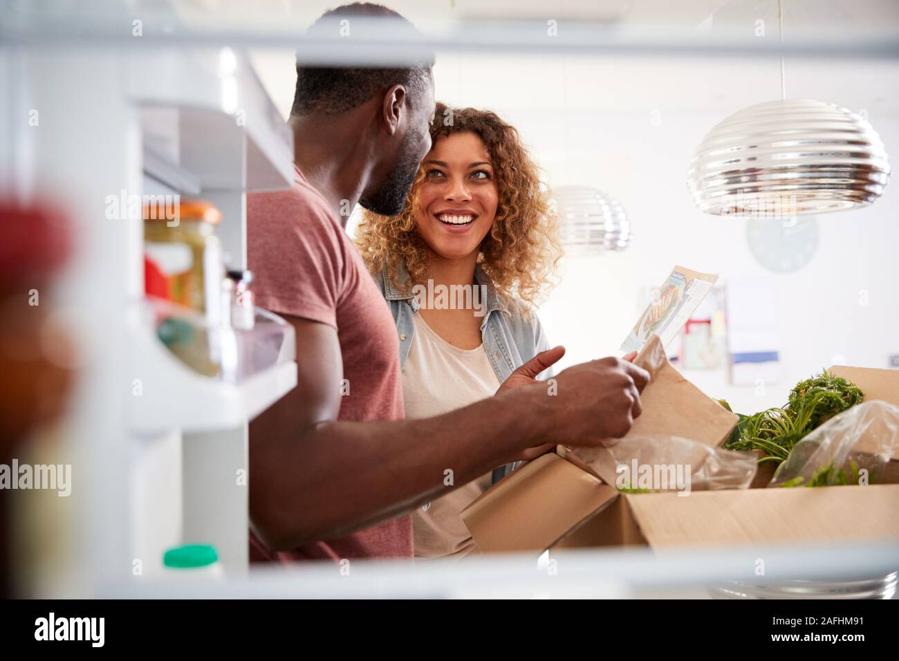 Vista dall'interno del frigorifero come giovane disimballare Online Home Consegna del cibo Foto Stock