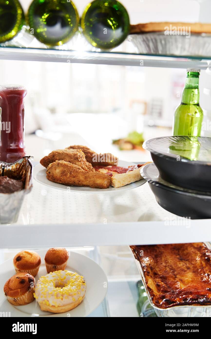 Vista dentro un frigorifero di malsano cibo da asporto e birra sugli scaffali Foto Stock