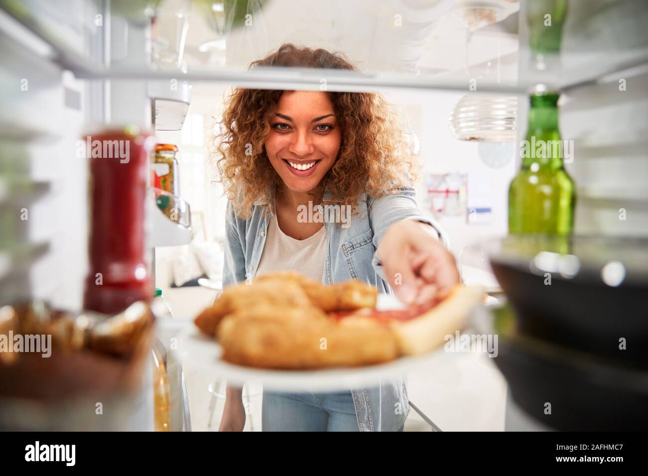 Vista dall'interno del frigorifero riempito con cibo da asporto come donna apre le porte Foto Stock