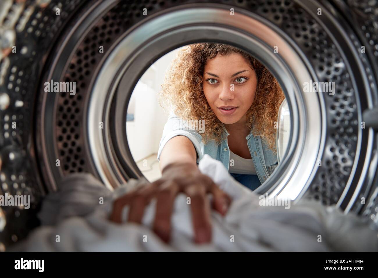 Vista dall'interno della macchina di lavaggio come donna bianco fa servizio lavanderia Foto Stock