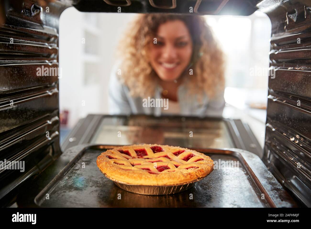 Vista guardando fuori dall'interno del forno come donna cuochi crostata di frutta Foto Stock