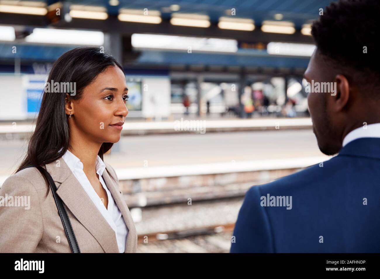 Imprenditore e imprenditrice pendolarismo per parlare di lavoro sulla piattaforma ferroviaria in attesa del treno Foto Stock
