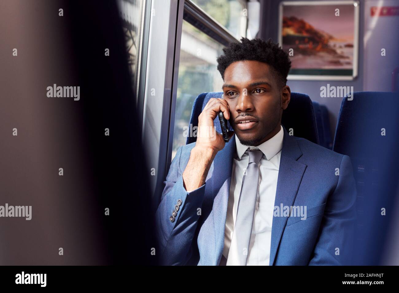Imprenditore seduto in treno Pendolari effettuare una chiamata sul telefono cellulare Foto Stock