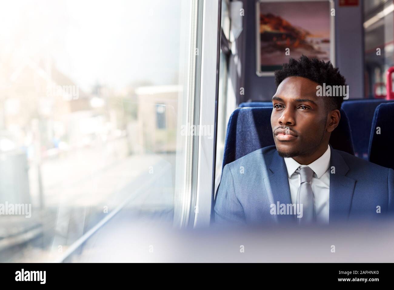 Imprenditore seduto in treno il pendolarismo a lavorare guardando fuori della finestra Foto Stock