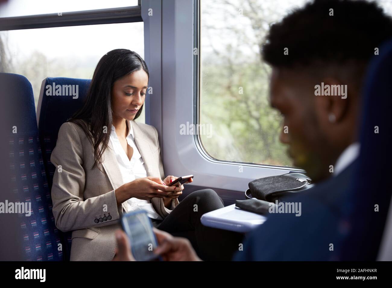 Business i passeggeri seduti in treno il pendolarismo a lavorare guardando i telefoni cellulari Foto Stock