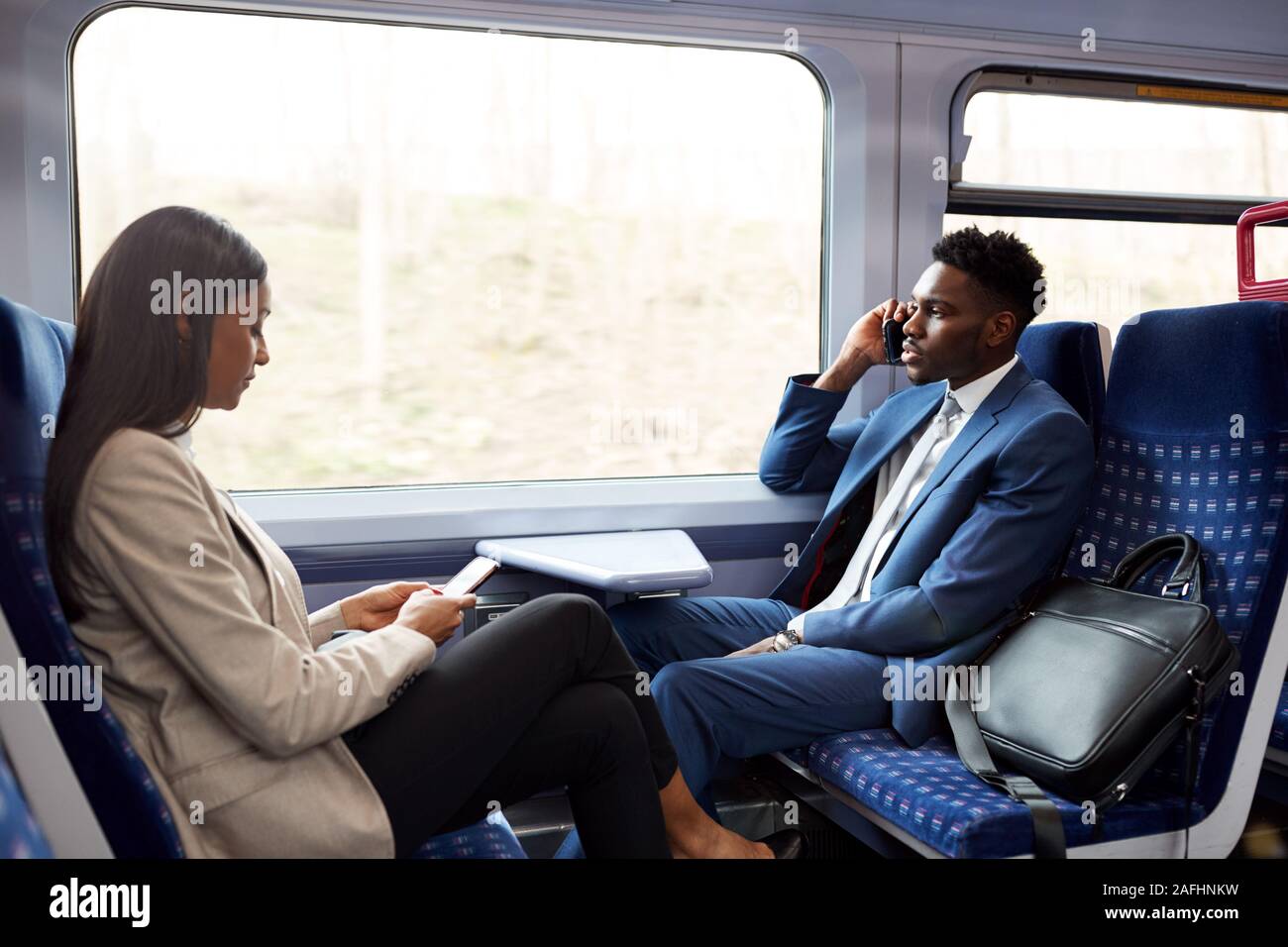 Business i passeggeri seduti in treno il pendolarismo di lavorare utilizzando i telefoni cellulari Foto Stock