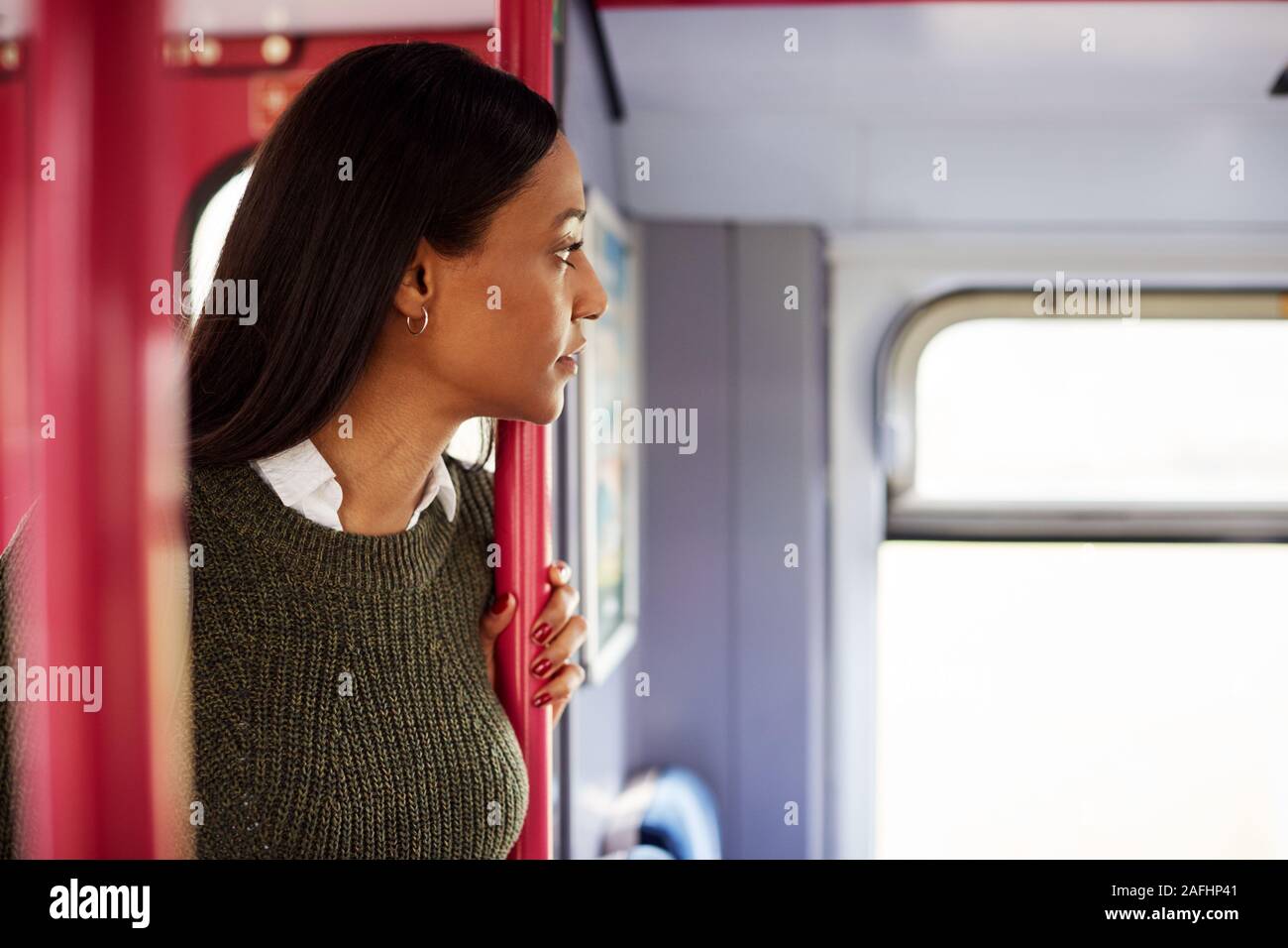 Femmina in piedi passeggero da porte In treno guardando fuori della finestra Foto Stock