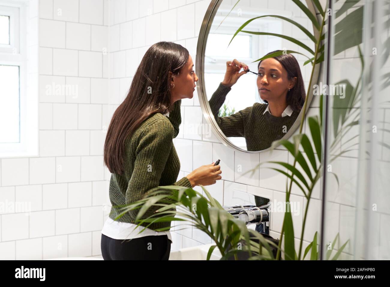Imprenditrice a casa e mettere su Make Up in Mirror prima di lasciare per il lavoro Foto Stock