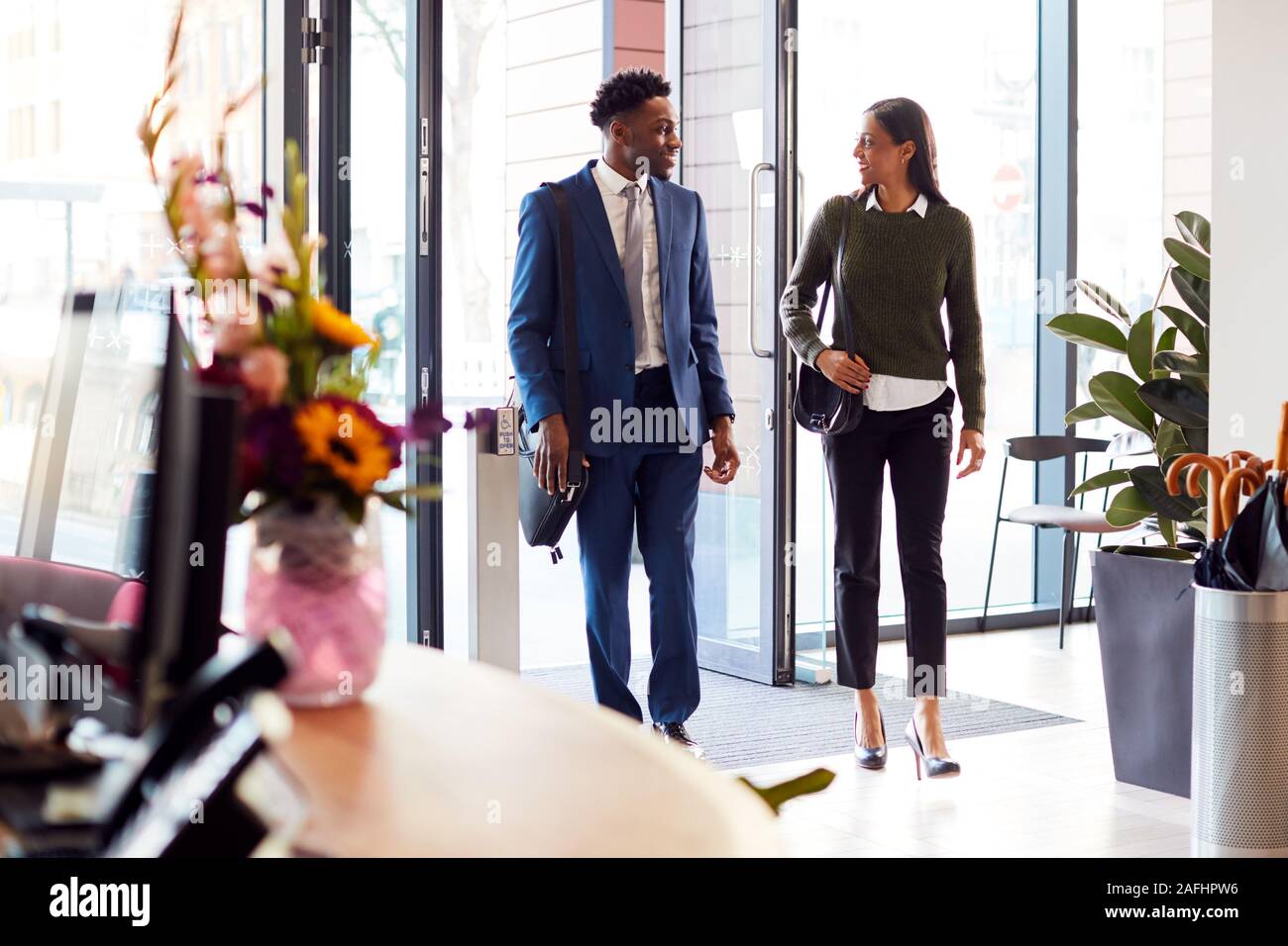 Imprenditore e imprenditrice che arrivano per lavorare in ufficio a piedi attraverso la porta Foto Stock