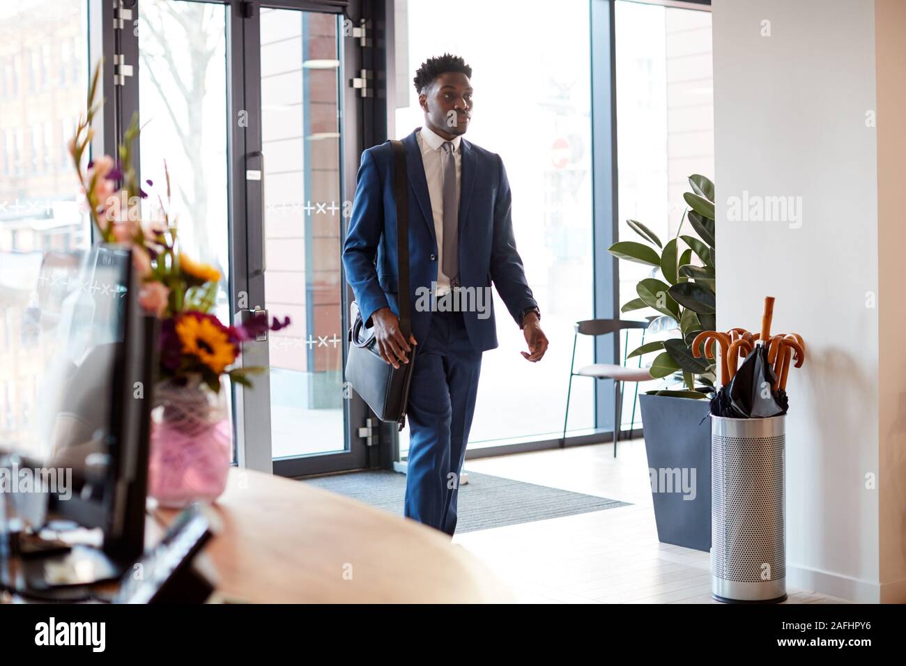 Imprenditore in arrivo per il lavoro in ufficio a piedi attraverso la porta Foto Stock