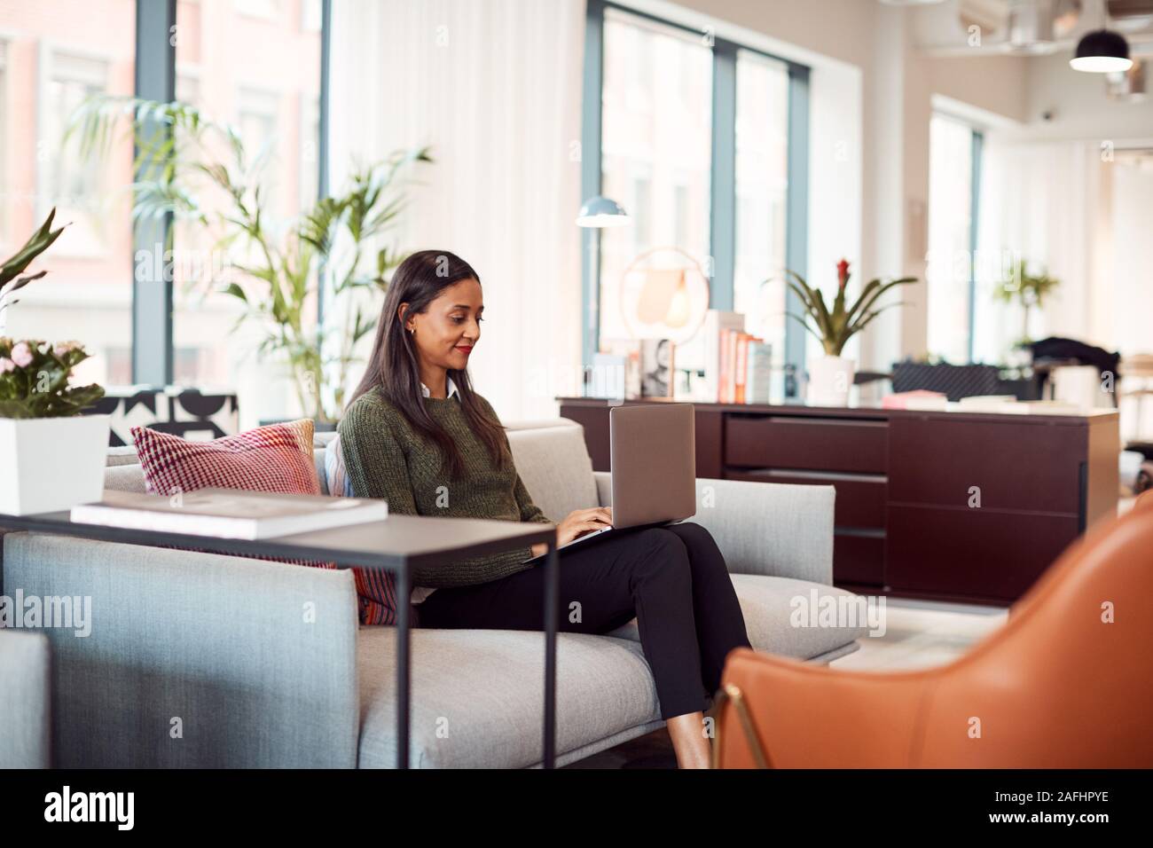 Imprenditrice seduti sul divano a lavorare sul computer portatile alla reception In Shared Workspace Office Foto Stock