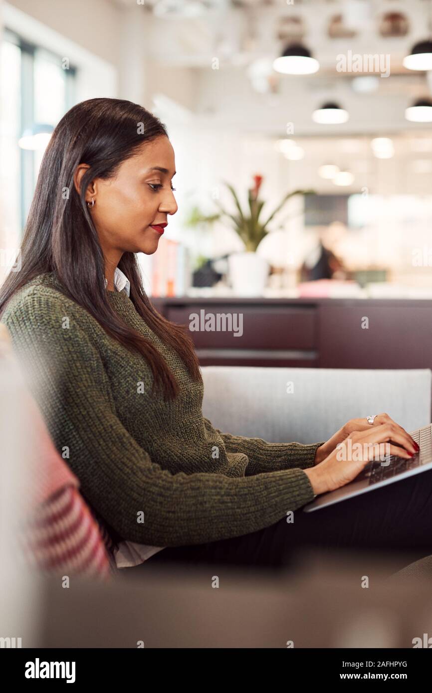 Imprenditrice seduti sul divano a lavorare sul computer portatile alla reception In Shared Workspace Office Foto Stock