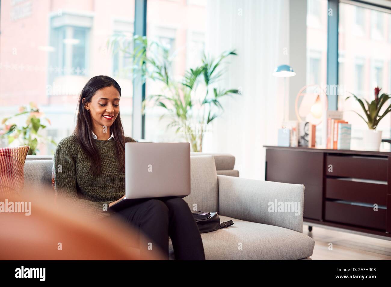 Imprenditrice seduti sul divano a lavorare sul computer portatile alla reception In Shared Workspace Office Foto Stock