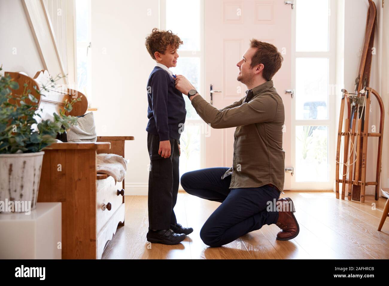 Unico padre a casa Getting figlio indossando divisa pronto per il primo giorno di scuola Foto Stock