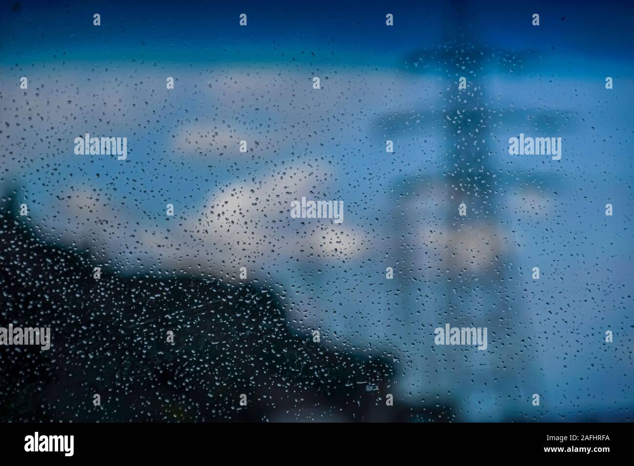 Al di fuori del potere focus pilone visibile attraverso una finestra coperta con gocce di pioggia. Il fuoco è sulle gocce di acqua sul parabrezza Foto Stock