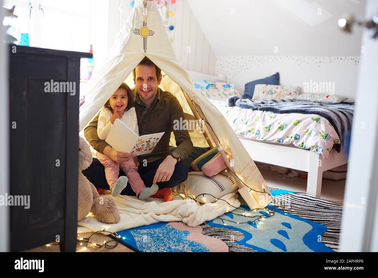Ritratto di sola lettura del Padre con la figlia In Den In camera da letto a casa Foto Stock