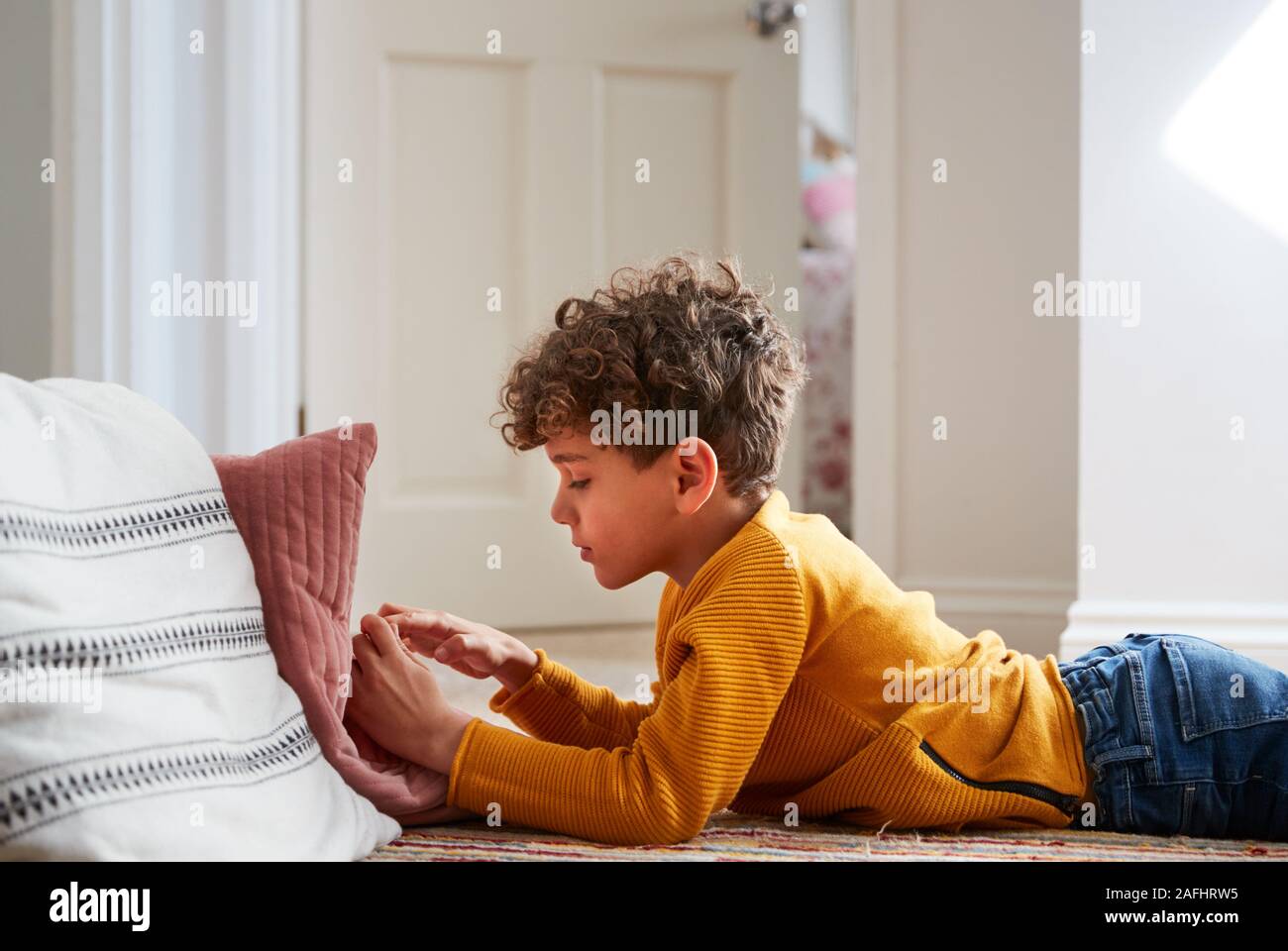 Ragazzo disteso sul pavimento della camera da letto di passare troppo tempo utilizzando il telefono cellulare Foto Stock
