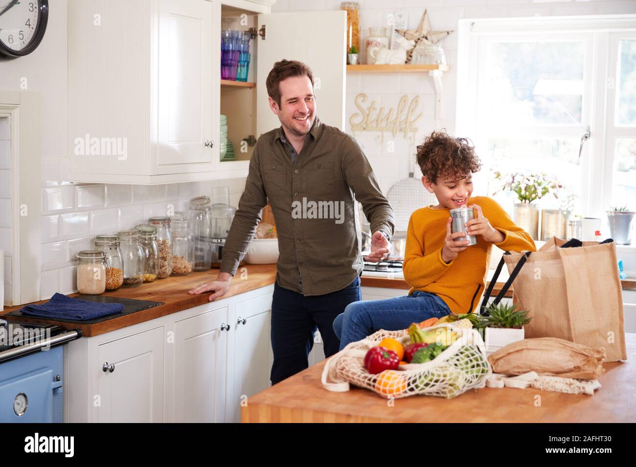 Padre e figlio di tornare a casa dal viaggio di shopping utilizzando plastica Sacchi libero disimballaggio generi alimentari in cucina Foto Stock