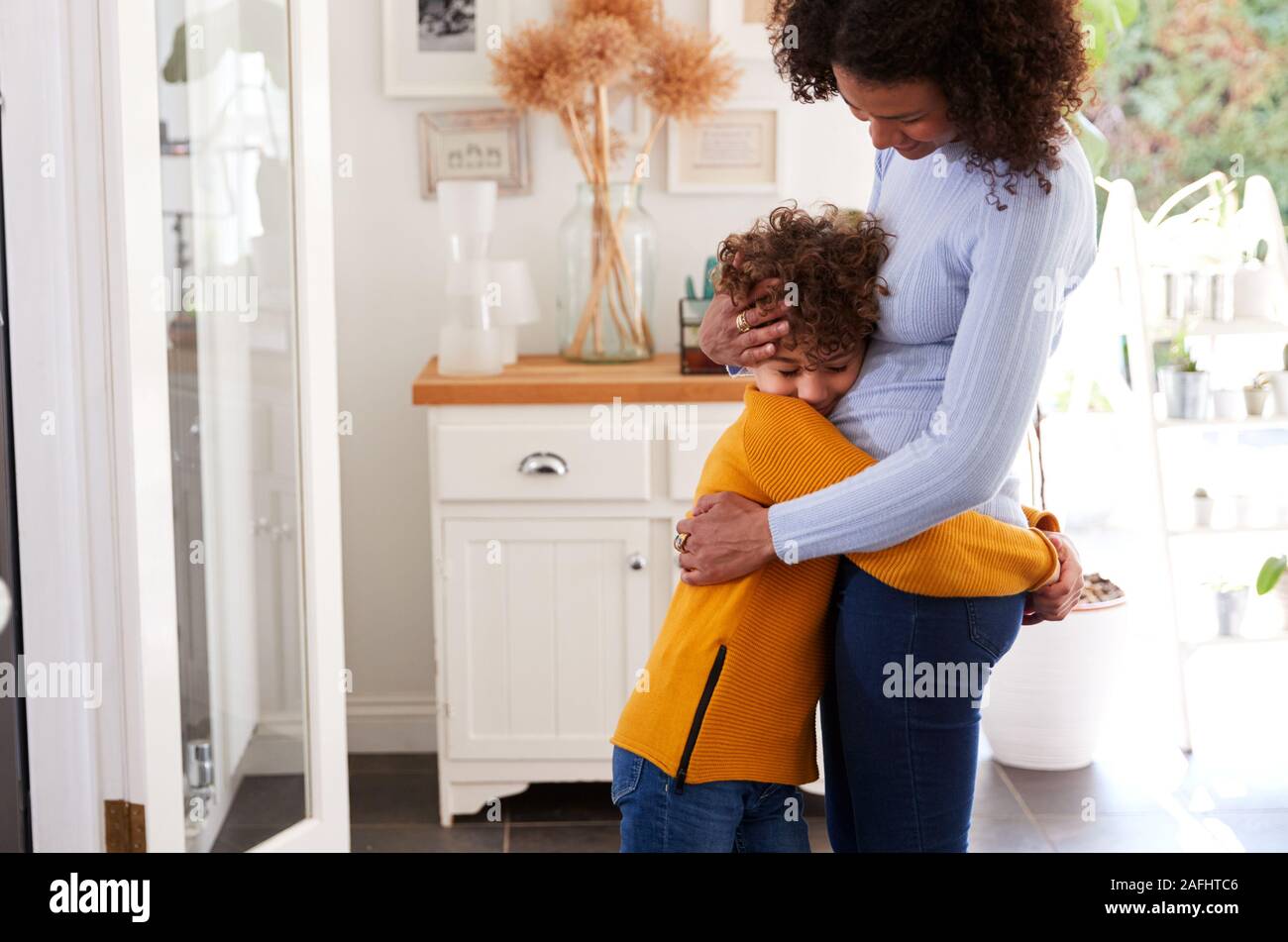 Amare il figlio dando madre abbraccio al chiuso in casa Foto Stock