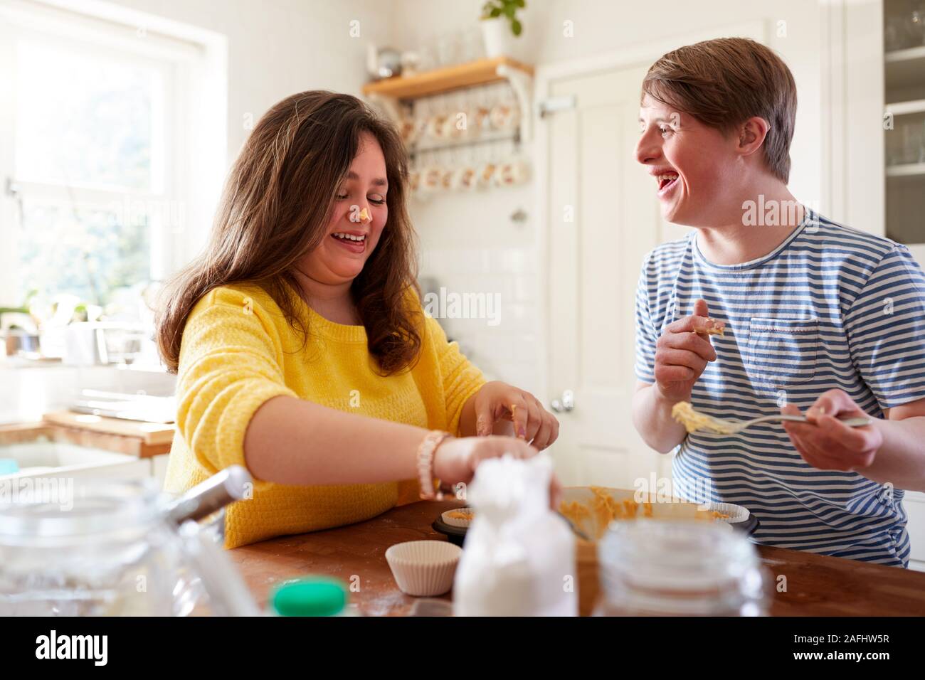 Giovani sindrome Downs giovane Divertirsi tortini di cottura nella cucina di casa Foto Stock