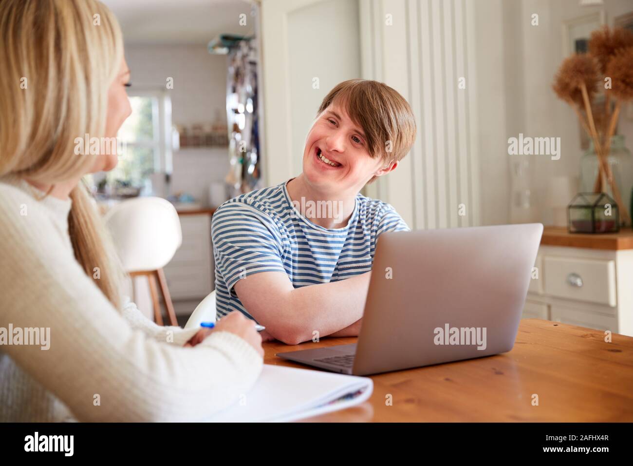 La sindrome di Down Uomo seduto con il Tutor di casa utilizzando computer portatile per la lezione a casa Foto Stock