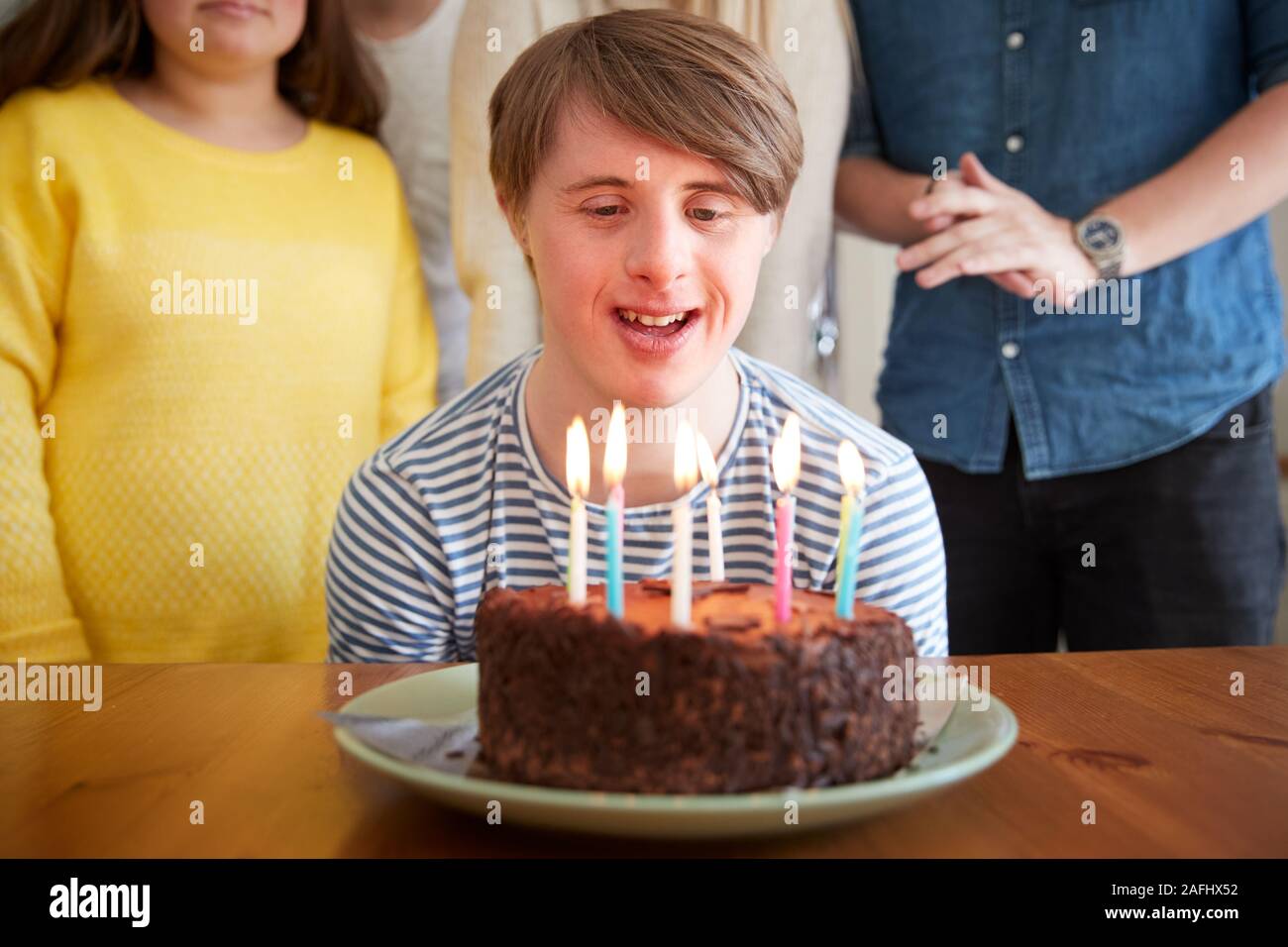 Giovani Downs uomo sindrome festeggia il compleanno a casa con torta Foto Stock